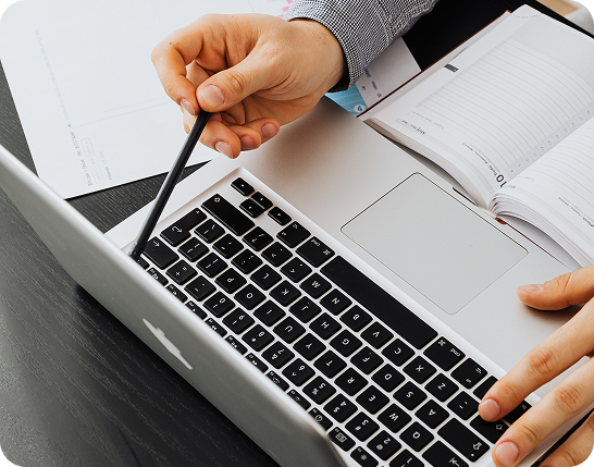 Hands reviewing paperwork beside a laptop